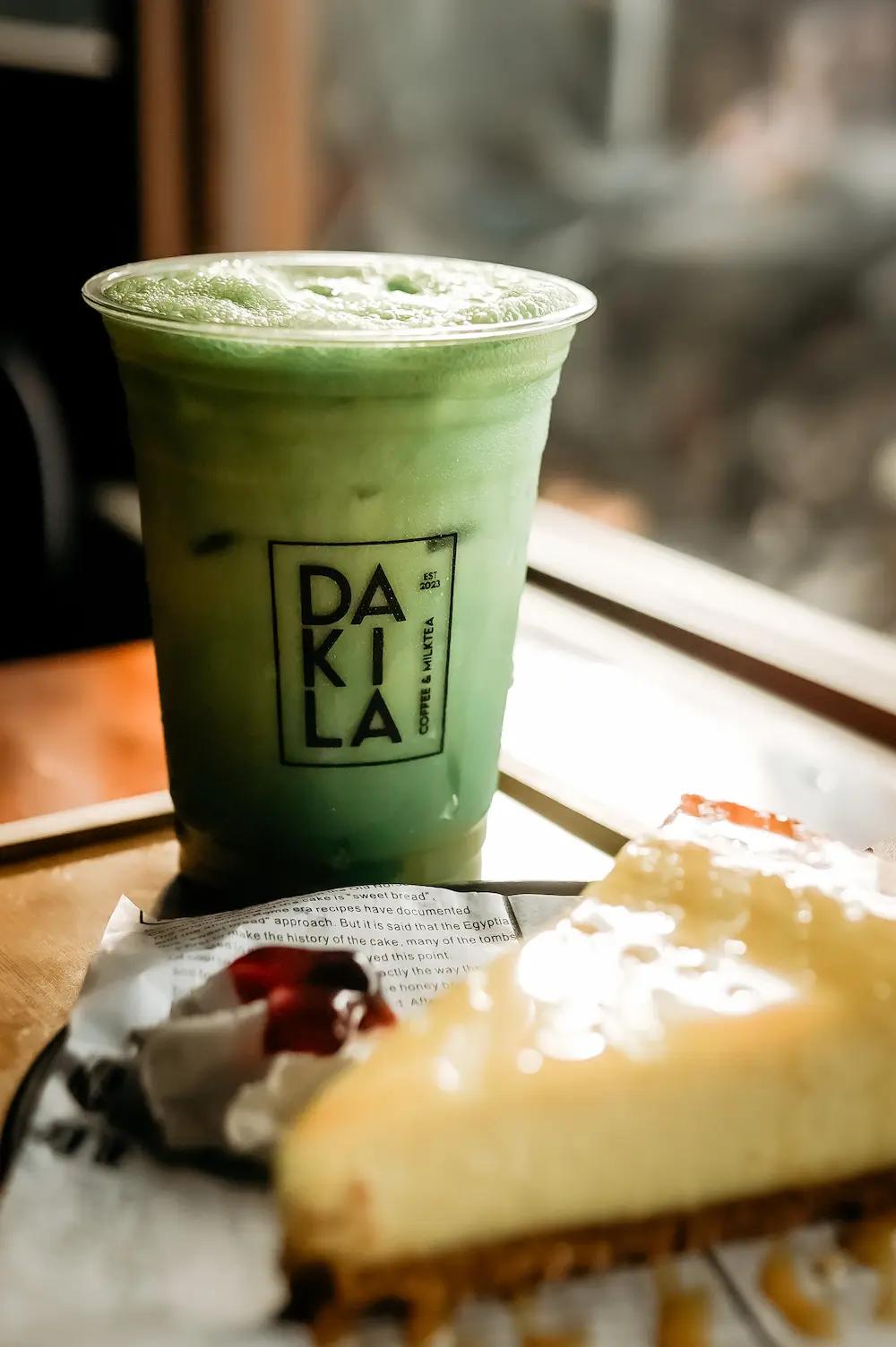 A Macha milktea and cheesecake on a table.